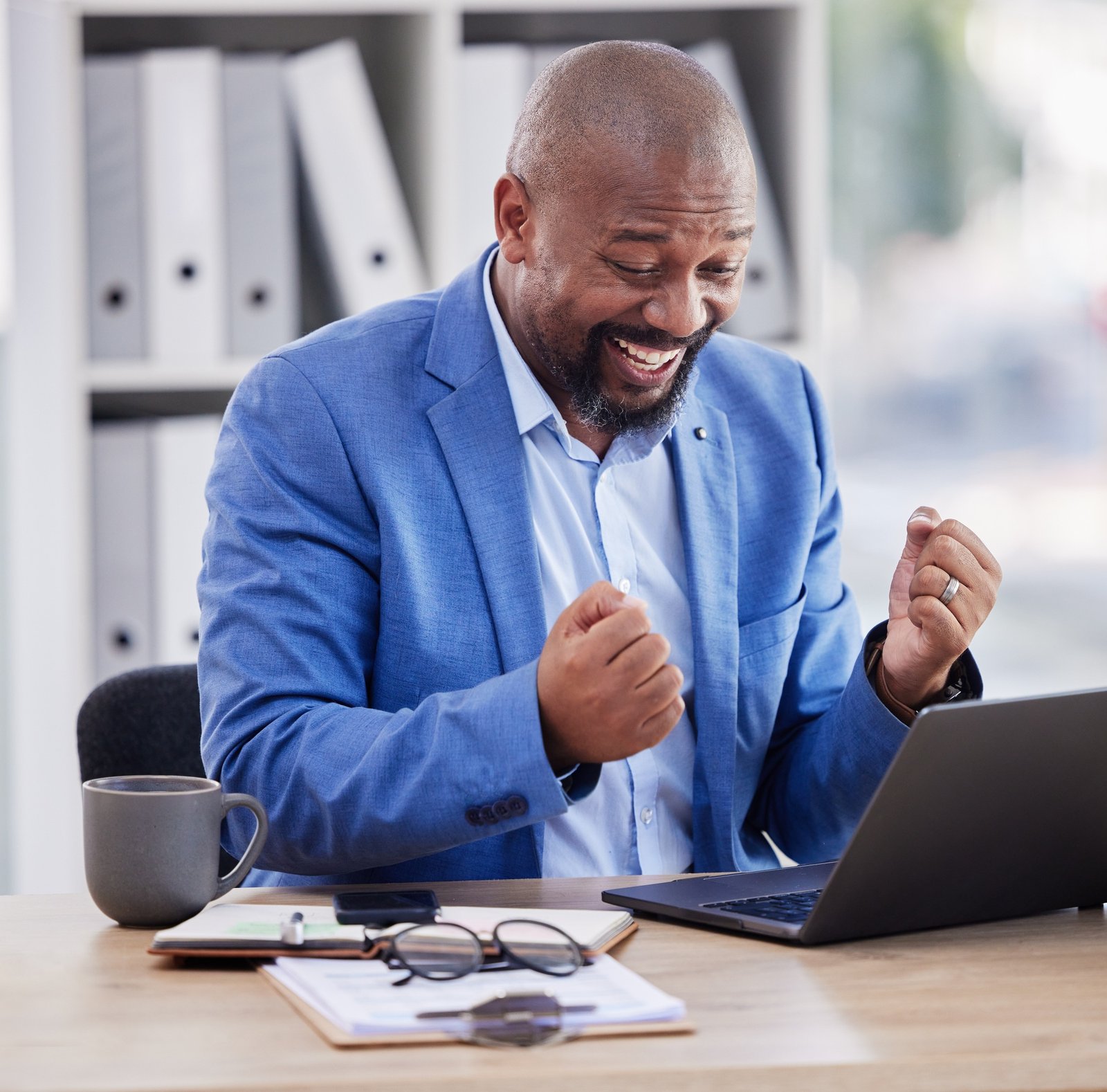 Happy, excited and black man at laptop in office, celebrate success and good news on online deal. W